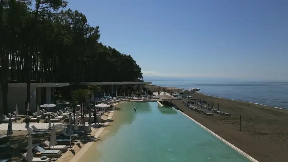 The club pool, the umbrellas and the black sand, a pass along the shore