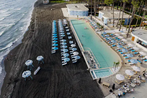 The club pool from above in July 2026, the loungers and the line of surf