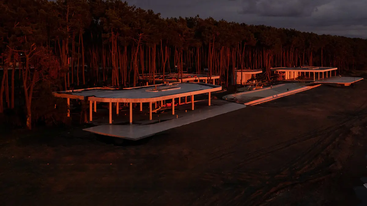 Slabs and columns of the beach club pavilions under construction in the forest at sunset